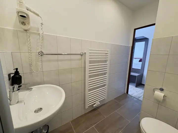 Bad mit Waschbecken, Handtuchheizung und Blick ins Zimmer