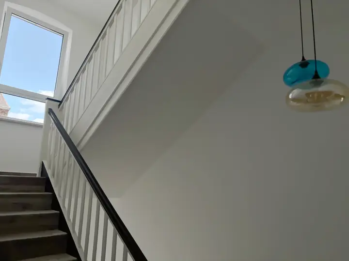 The hotel's staircase: wooden steps with a white banister and dark handrail, a window at the top