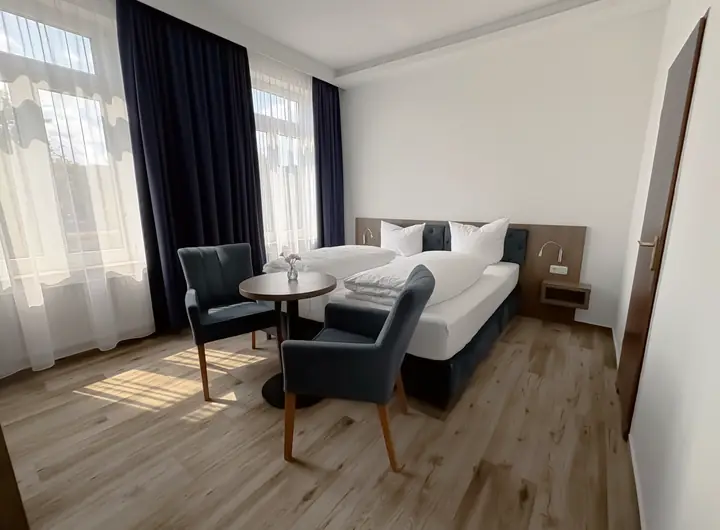 Sitzecke mit zwei blauen Sesseln und kleinem Tisch am Fenster
