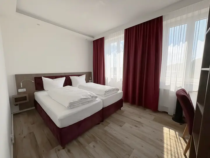 Doppelbett zwischen zwei Fenstern im weinroten Zimmer